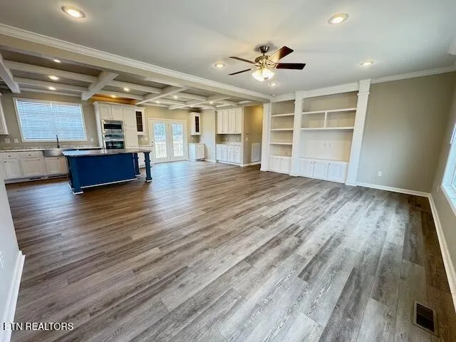 an empty room with wooden floor and ceiling fan