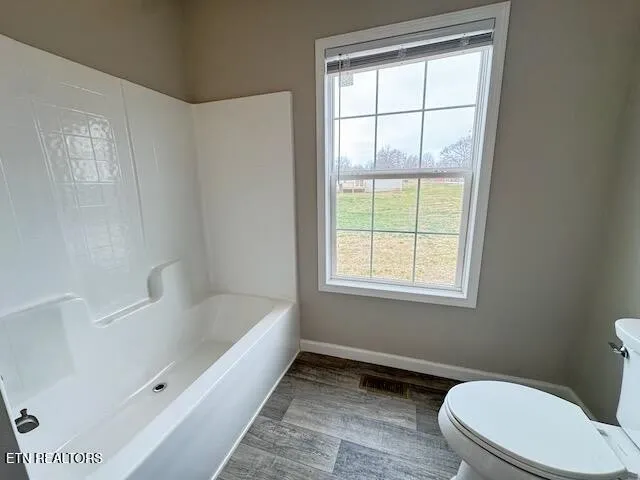 a bathroom with a bathtub toilet and window