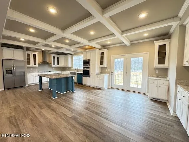 a large white kitchen with stainless steel appliances kitchen island granite countertop a stove and a refrigerator