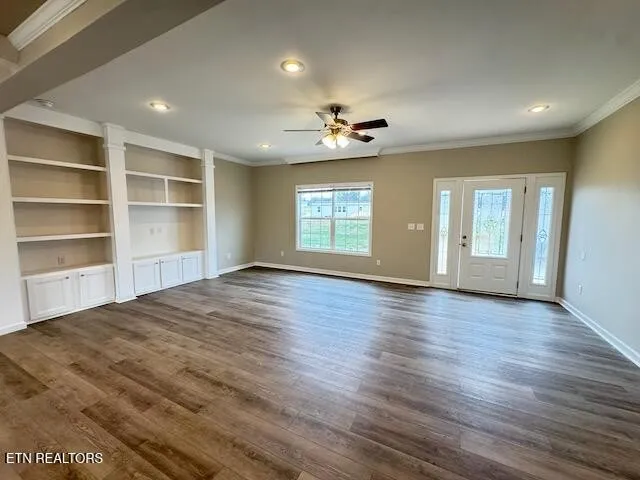 a view of an empty room with a window and wooden floor