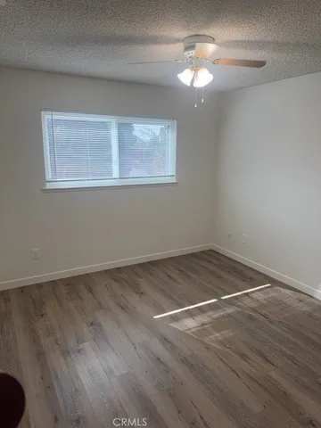 a view of empty room with wooden floor and fan