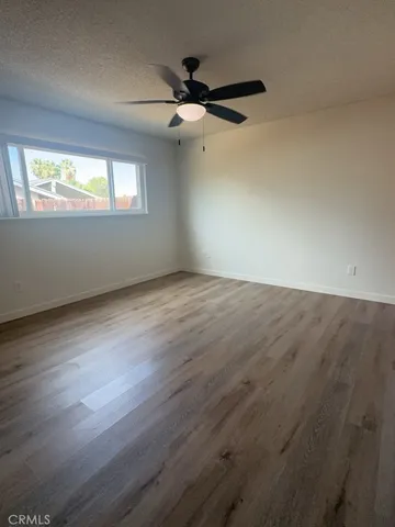 an empty room with wooden floor fan and windows