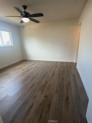 an empty room with wooden floor fan and windows