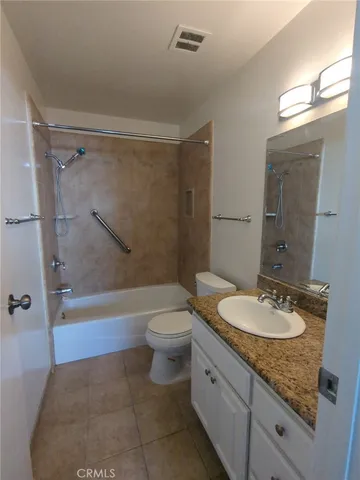 a bathroom with a granite countertop sink toilet mirror and bathtub