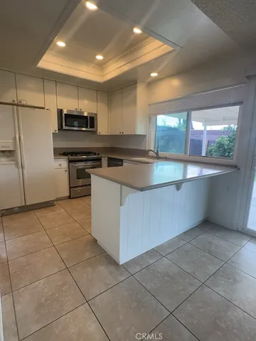 a kitchen with stainless steel appliances a sink a stove a microwave a refrigerator a microwave and cabinets