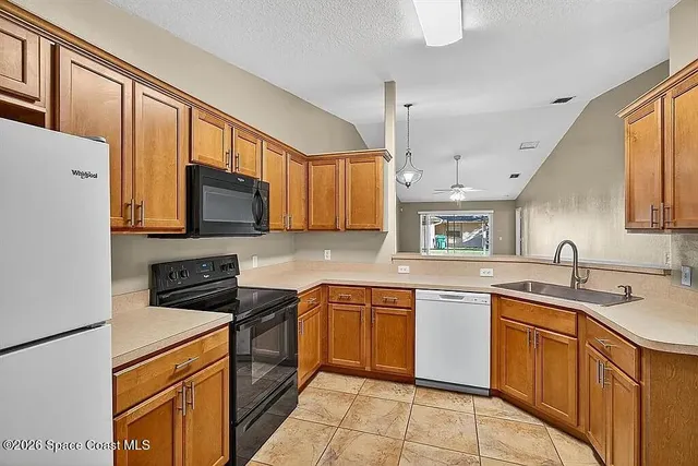 a kitchen with stainless steel appliances granite countertop a sink stove refrigerator and cabinets
