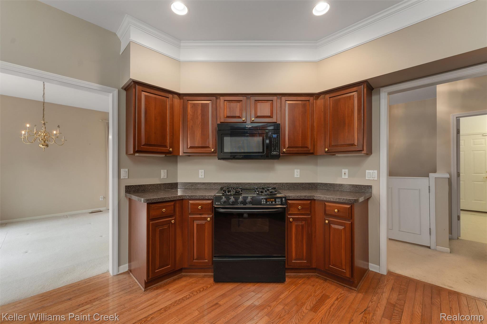 1685 Maple Creek Court Rochester, MI 48306 - Photo 12 of 49 Kitchen featuring black appliances, a chandelier, light wood-type flooring, wood finish cabinetry, and crown molding