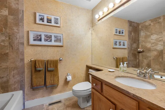 a bathroom with a granite countertop toilet sink and mirror
