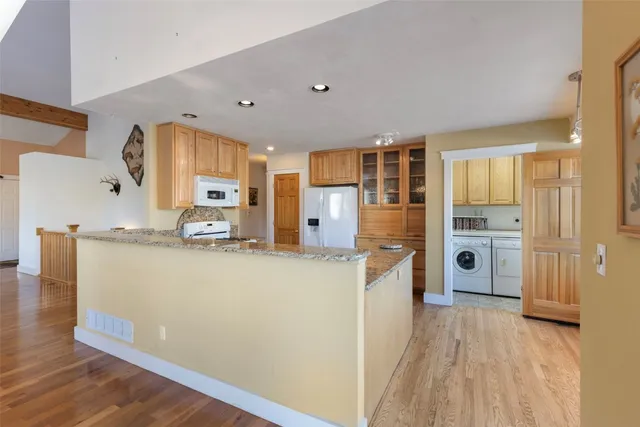a kitchen with stainless steel appliances granite countertop a refrigerator a stove and a wooden floors