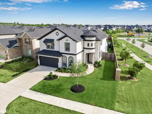 a view of a white house with a big yard plants and large tree