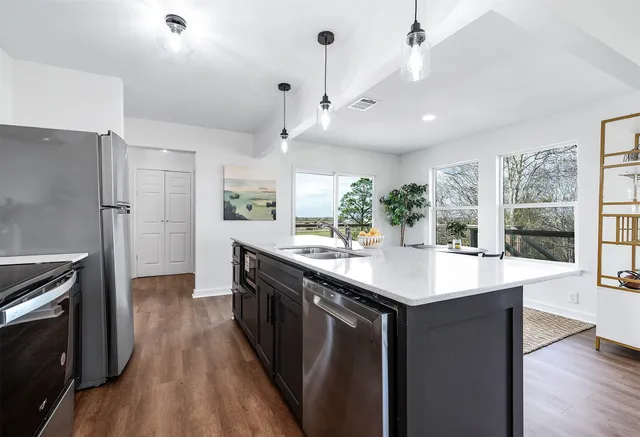 a kitchen with stainless steel appliances granite countertop a sink a stove and a refrigerator