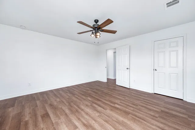 a view of a room with wooden floor and a ceiling fan