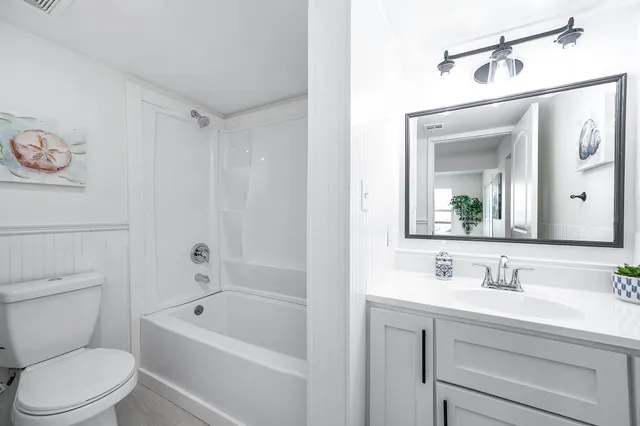 a bathroom with a sink a mirror a toilet and a bathtub