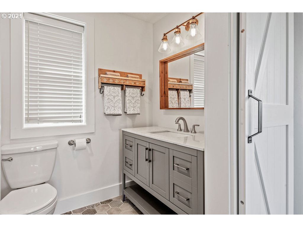 320 Northwest 194th Street Ridgefield, WA 98642 - Photo 28 of 32 a bathroom with a toilet a sink a mirror a window and vanity