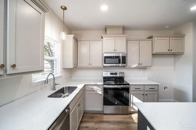 a kitchen with stainless steel appliances a stove a sink a microwave and cabinets