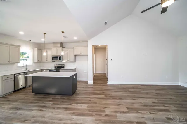 a large kitchen with stainless steel appliances a large counter top a stove a microwave and a refrigerator