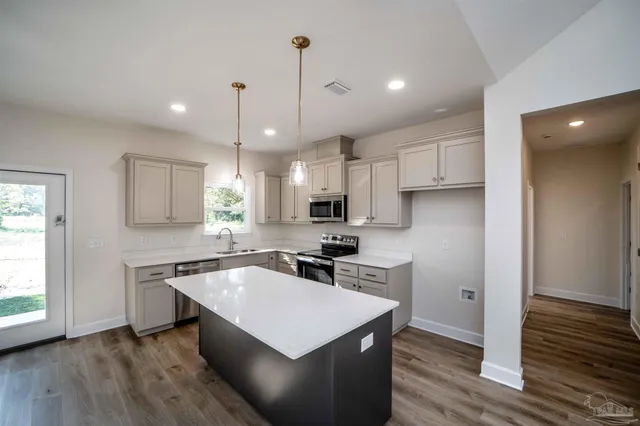 a kitchen with kitchen island a sink a stove a wooden floor and a window