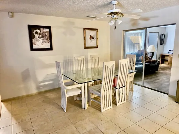 a dining room with furniture and a chandelier fan