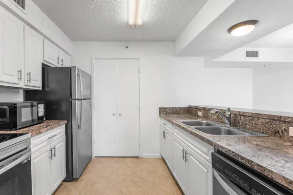 a kitchen with granite countertop a sink stove and refrigerator