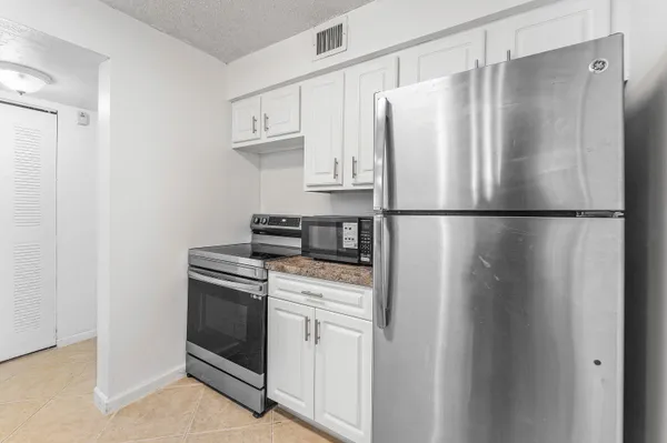 a white refrigerator freezer and a stove sitting inside of a kitchen