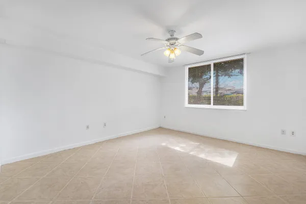 an empty room with windows and fan