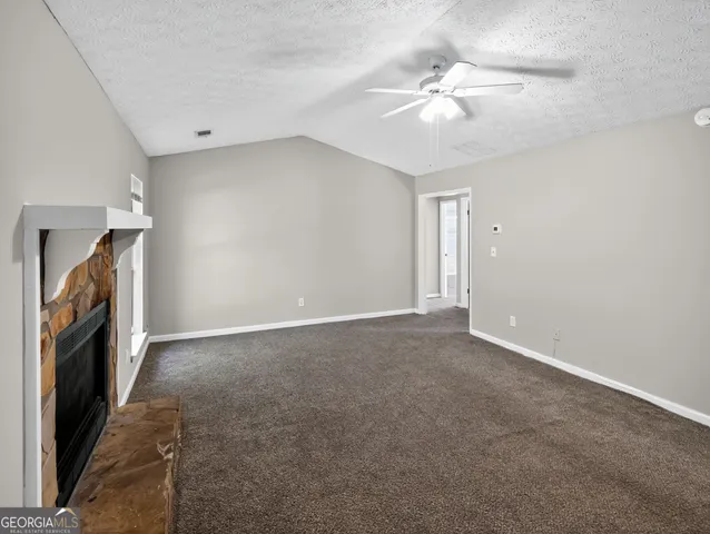 a view of an empty room with a ceiling fan window and a fireplace