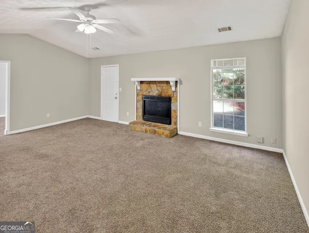 an empty room with windows and fan