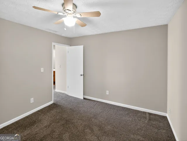an empty room with a chandelier fan and windows