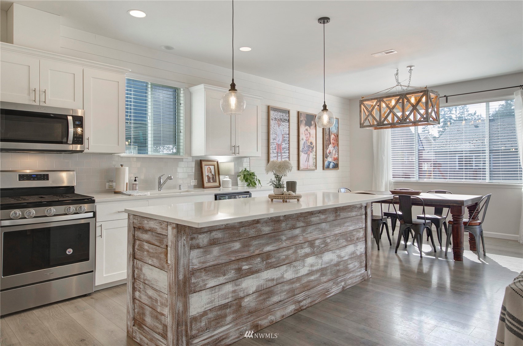 20206 18th Ave Court East Spanaway, WA 98387 - Photo 5 of 37 a kitchen with stainless steel appliances granite countertop a stove a refrigerator a kitchen island a dining table and chairs with wooden floor