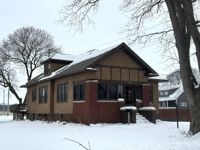 a front view of a house with a yard covered with snow