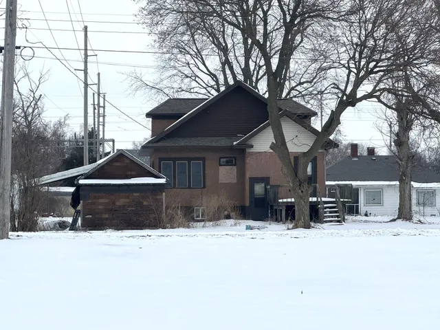 a front view of a house with a yard covered in snow