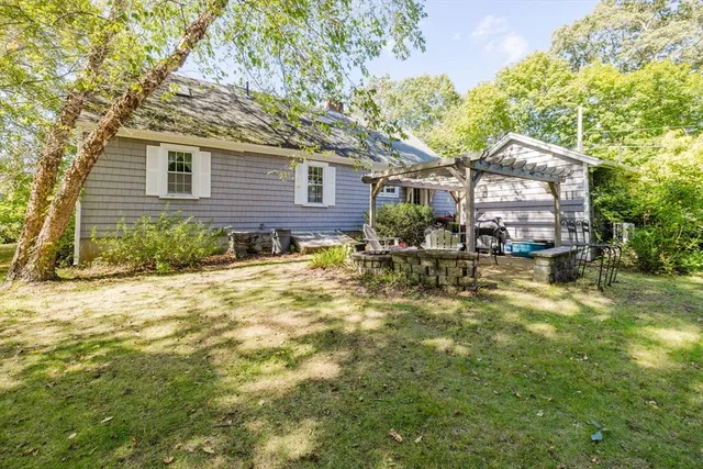 a backyard of a house with table and chairs under an umbrella