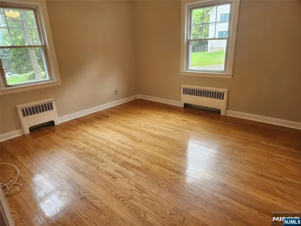 an empty room with wooden floor fan and windows