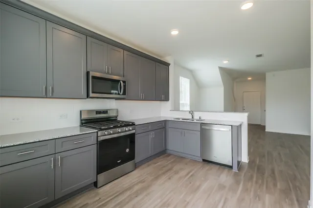 a kitchen with stainless steel appliances granite countertop a stove a sink and a microwave