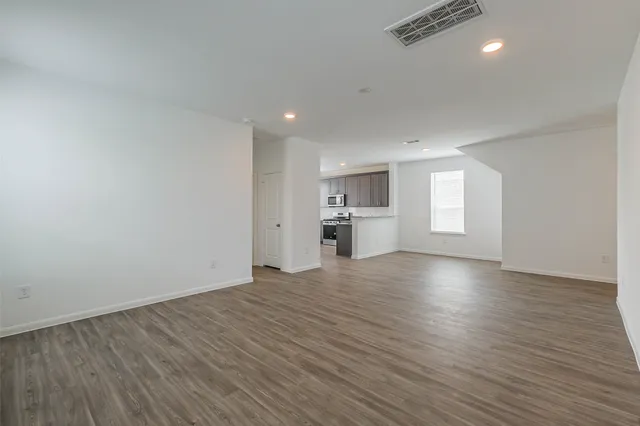 a view of empty room with wooden floor and windows