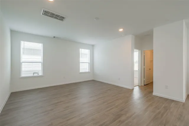 an empty room with wooden floor and windows