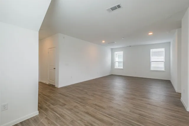an empty room with wooden floor and window