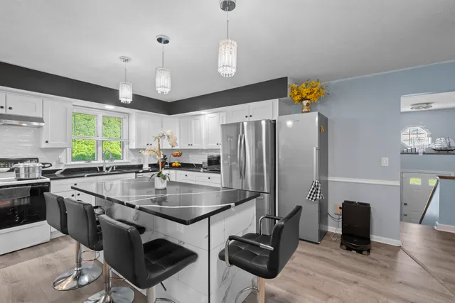 a kitchen with stainless steel appliances granite countertop a sink a stove and a refrigerator