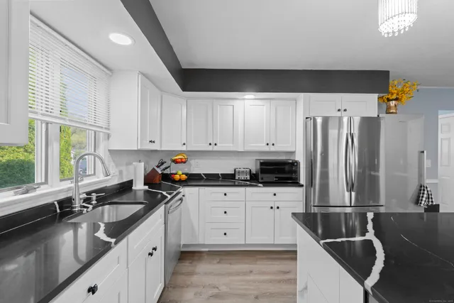a kitchen with granite countertop a sink a counter top space appliances and cabinets