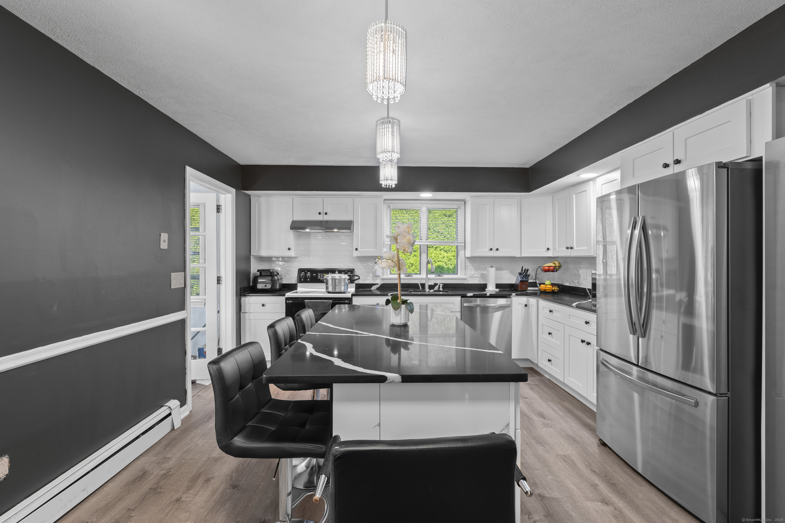 63 Johl Drive Groton, CT 06340 - Photo 8 of 40 a kitchen with stainless steel appliances granite countertop a refrigerator a stove a sink dishwasher a dining table and chairs with wooden floor