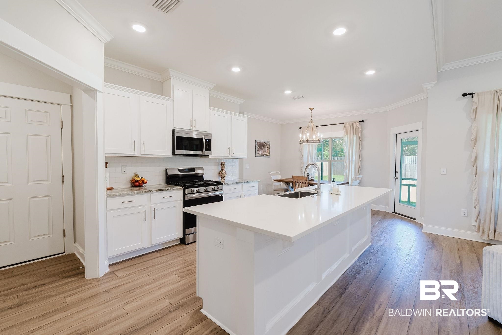 7872 Calverton Street Foley, AL 36535 - Photo 36 of 76 Open-concept kitchen featuring an expansive island with a solid surface countertop, wood-finish flooring, white cabinetry, stainless steel appliances, and recessed lighting