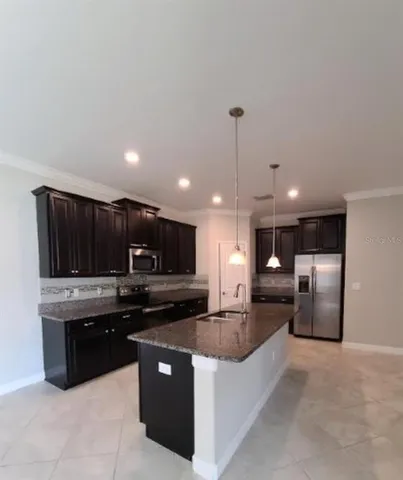 a large kitchen with stainless steel appliances kitchen island granite countertop a refrigerator a stove a microwave a sink and a counter top space