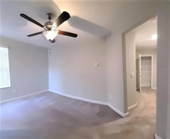 an empty room with windows and fan