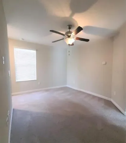 an empty room with a window and a fan