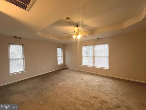 an empty room with windows and chandelier fan
