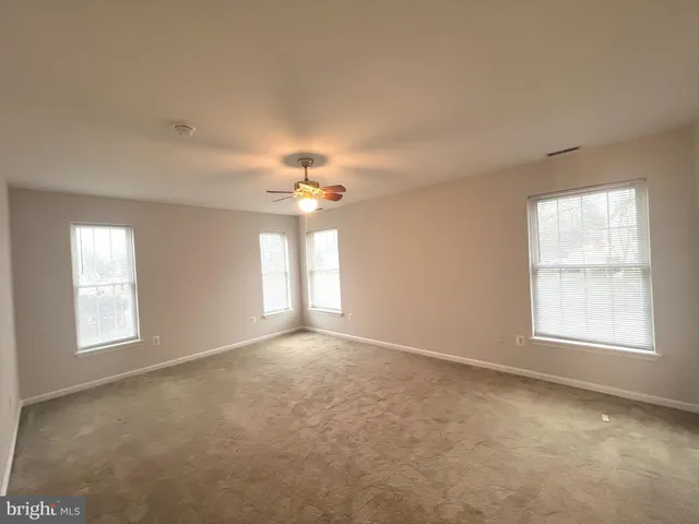 an empty room with windows and chandelier fan