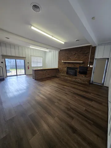 an empty room with wooden floor fireplace and windows