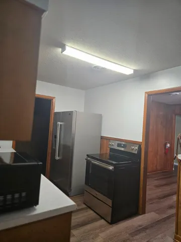 a view of a refrigerator in kitchen and an empty room