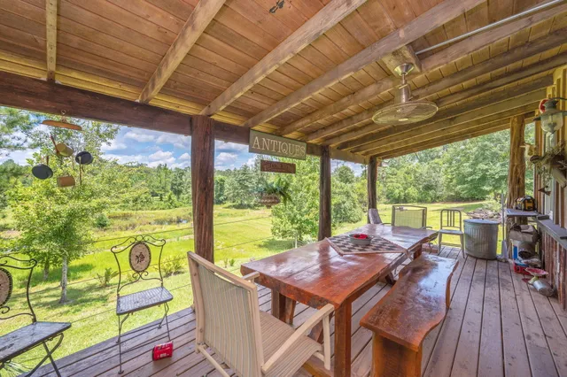a view of a patio with table and chairs in front of a house with wooden floor