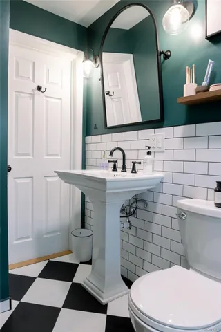 a bathroom with a toilet a sink and mirror